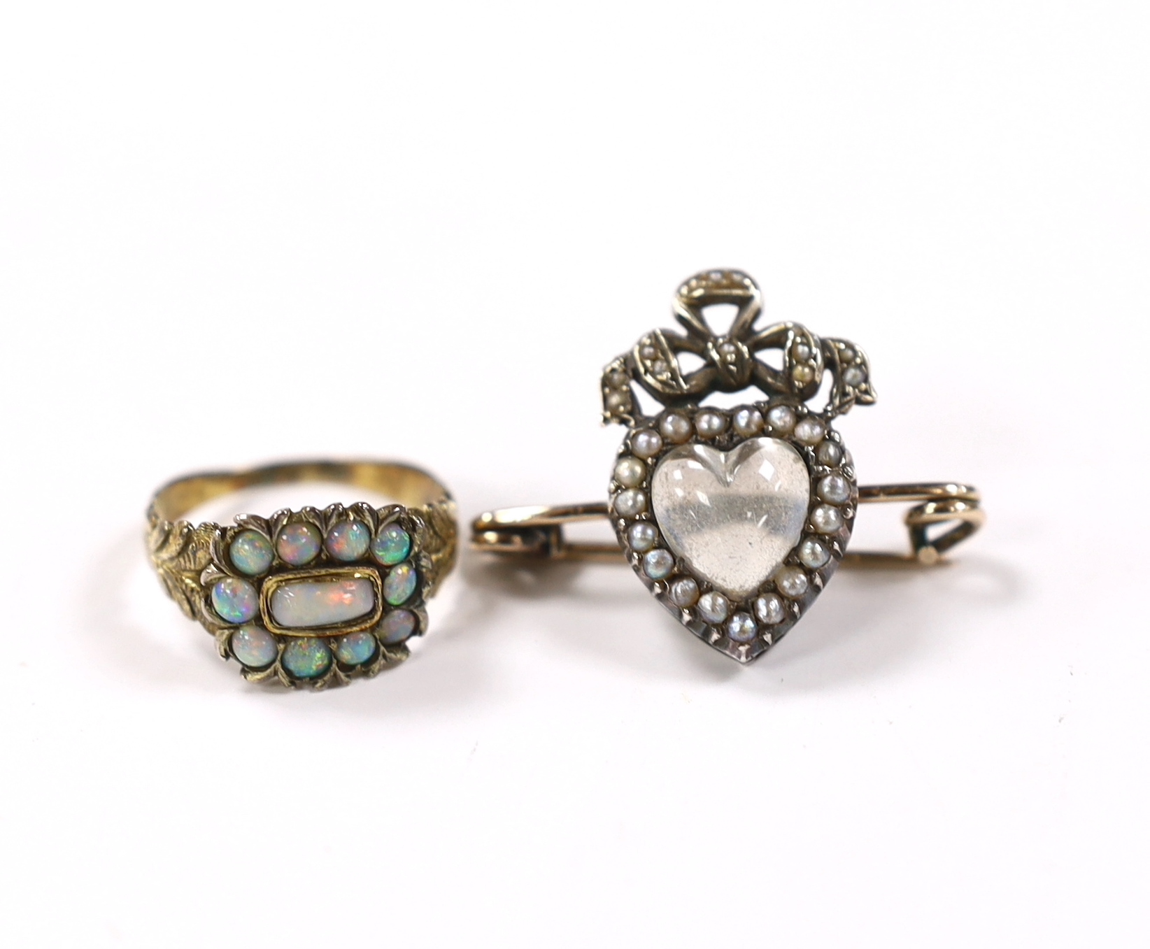 A Victorian yellow metal and white opal cluster set ring, size O and a similar moonstone and split pearl cluster set bar brooch with heart motif.